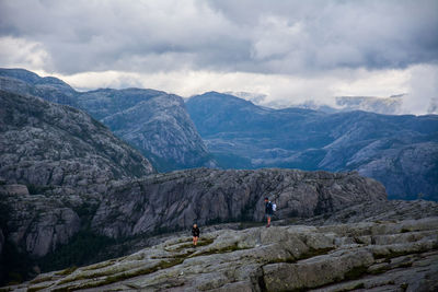 High angle view of man and woman on rocky mountains against cloudy sky