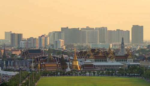 Buildings in city against clear sky during sunset