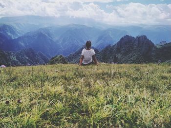 Rear view of man on field against mountain range