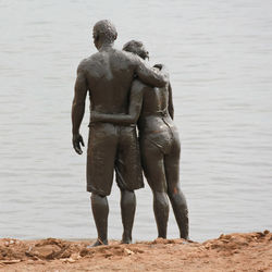 Rear view of muddy couple at beach