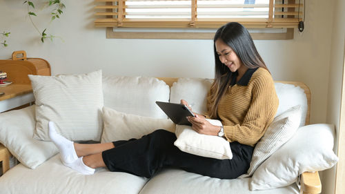 Young woman sitting on bed at home