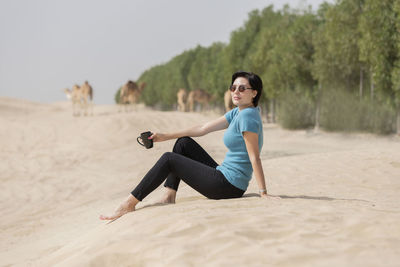 Side view of woman sitting on sand