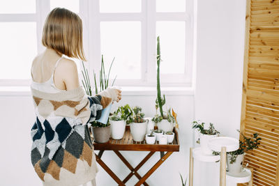 Rear view of woman standing by potted plants