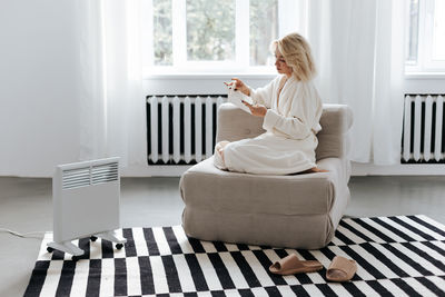 Rear view of woman sitting on bed at home