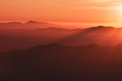 Scenic view of silhouette mountains against orange sky