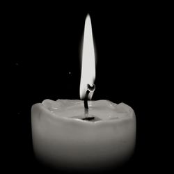 Close-up of lit candle in darkroom