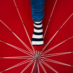 Low section of person standing on red umbrella