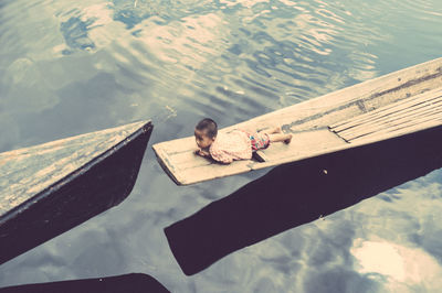 High angle view of boy sitting on lake