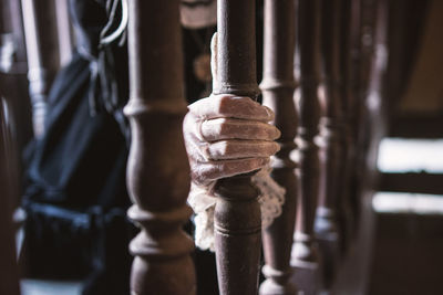 Close-up of hand holding wooding fence in a hallway