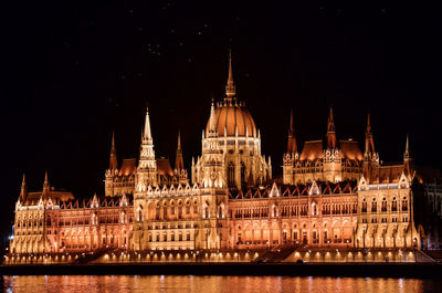 Danube river in front of illuminated hungarian parliament building at night