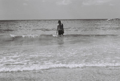 Man standing in sea against sky