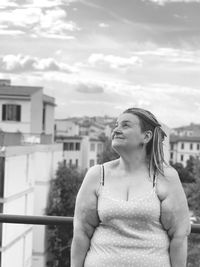 Young woman looking away while standing against buildings