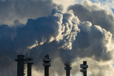 Smoke stacks pour pollution backlit by sunrise