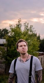 Portrait of young man standing against trees