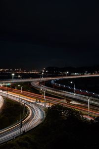 Light trails on road in city against sky at night