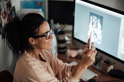 Portrait of woman using mobile phone while sitting on table