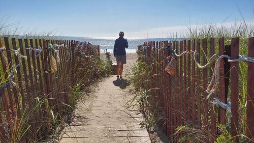 Full length of man standing on footpath against sky