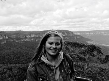 Portrait of smiling beautiful woman at blue mountains national park against cloudy sky