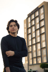 Portrait of young man looking away against built structure