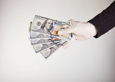 Close-up of hand holding paper over white background