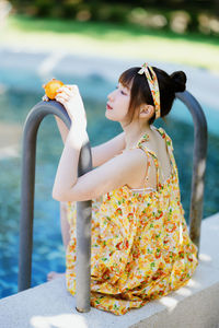 Rear view of young woman standing by railing