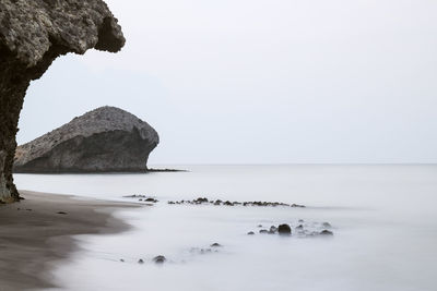 Rocks in sea against clear sky