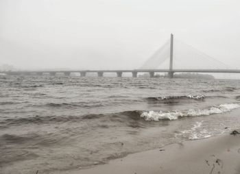 Suspension bridge over sea against clear sky