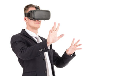 Businessman wearing virtual reality simulator while gesturing against white background