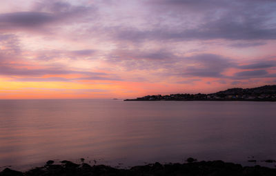 Scenic view of sea against dramatic sky during sunset