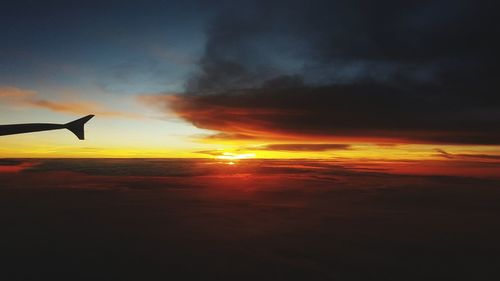 Airplane wing against sky during sunset