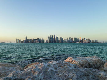 Scenic view of sea and buildings against clear sky