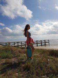Woman standing by sea against sky