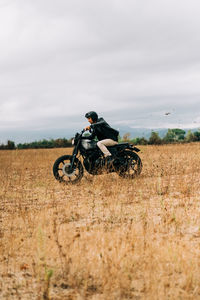 Man riding motorcycle on field against sky