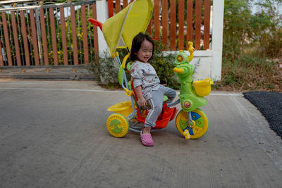 Smiling girl sitting in tricycle on footpath
