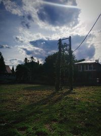 Trees on field against cloudy sky