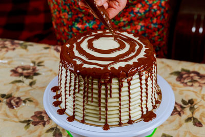 Cropped hands icing cake with chocolate