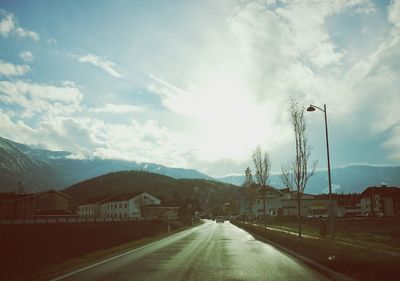 Road by trees and mountain against sky