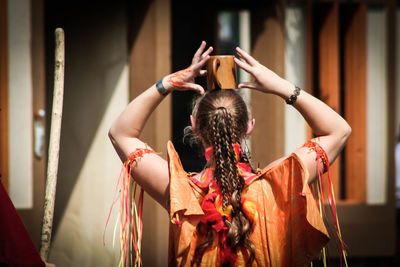 Rear view of woman balancing cup on head