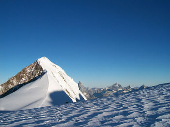 Scenic view of snowcapped mountains against clear blue sky