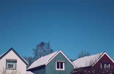 Houses and trees against clear sky during winter