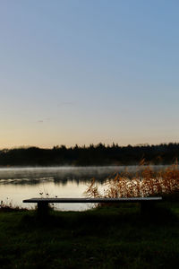 Scenic view of lake against clear sky during sunset