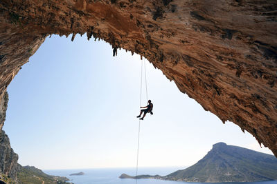 Greece, kalymnos, climber abseiling in grotto