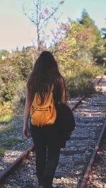 Rear view of woman standing on railroad track