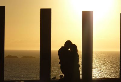 Silhouette friends on beach against clear sky during sunset