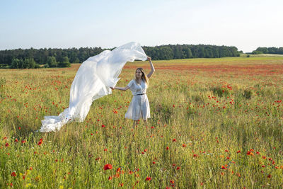 Rear view of woman with arms outstretched on field