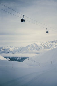 Overhead cable car against snowcapped mountains against sky