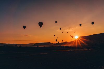 Hot air balloons flying over land during sunset