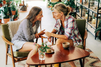 Two stylish female girlfriends are talking while sitting in a cafe.