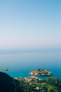 High angle view of townscape by sea against blue sky