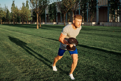 Full length of young man exercising on field